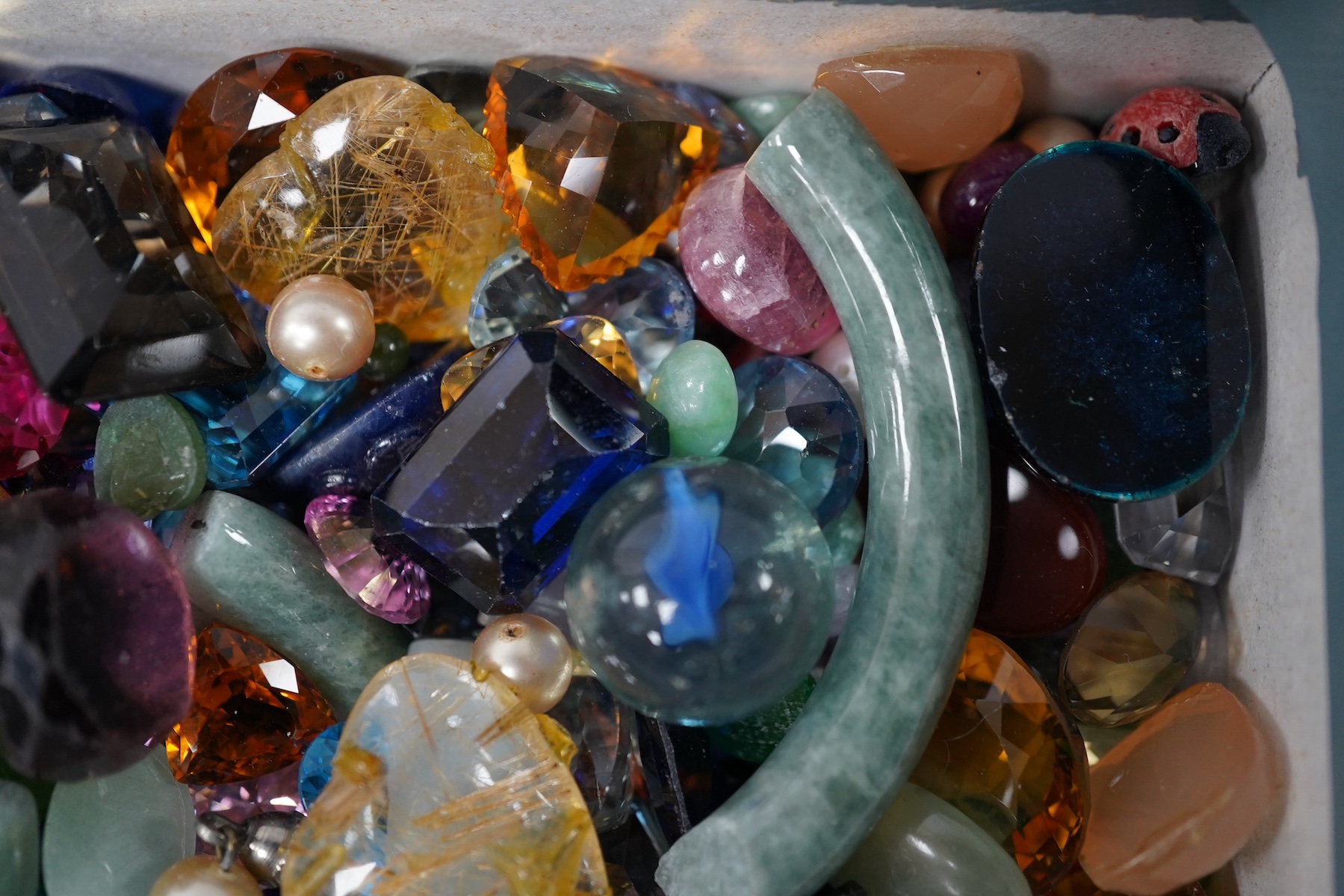 A group of assorted unmounted cut gemstones, including tourmaline, citrine etc. and a damaged jade bangle. Condition - poor to fair to good